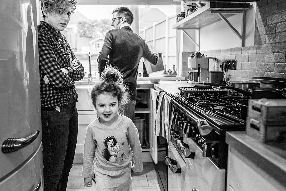 girl running from the kitchen with mum looking at her from family documentary photography session